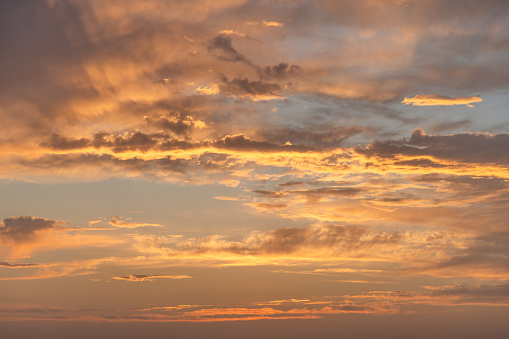 The sky at dusk is enveloped in a tapestry of gold and amber, with clouds scattered across, creating an ethereal backdrop perfect for enhancing any creative project