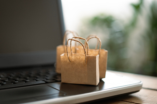 Miniature shopping bags standing on laptop