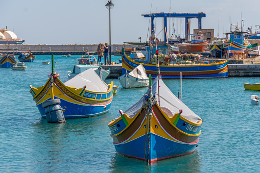 Marsaxlokk, Malta - March 23rd 2022: The traditional Maltese fishing boat called a Luzzu moored in Marsaxlokk Harbour. They are brightly coloured with eyes on the bow known as the Eye of Horus to protect the fishermen while at sea.