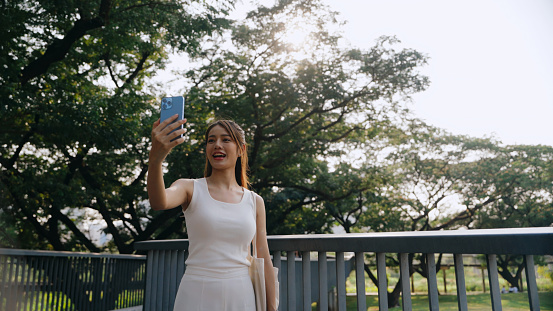 A joyful woman captures a sunny selfie moment, surrounded by nature's tranquility