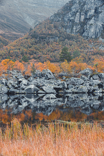 Still lake reflects rocks and autumn colored trees