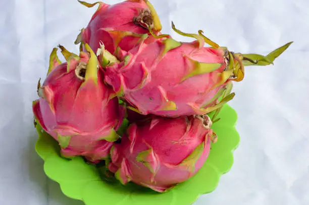Close-Up High-Angle View Of Dragon Fruits On A Green Plate Against White Background