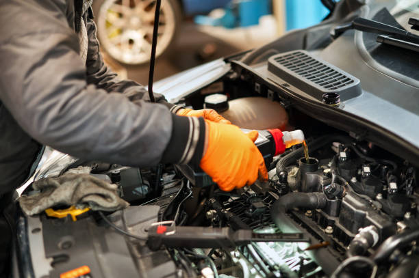 istock Unrecognizable mechanic in gloves pouring oil in engine 2148132638