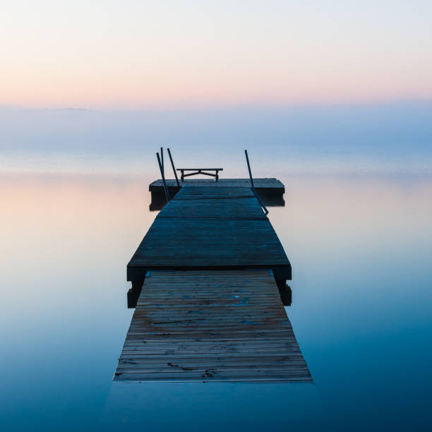 istock Wooden jetty floating on a calm and misty lake 2148132738