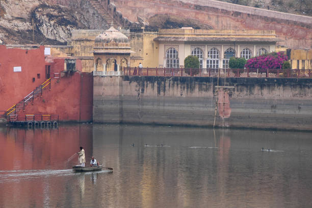 Rajasthan, India - March 10, 2006: Men sailing a boat on Maotha Lake in front of Amber Fort