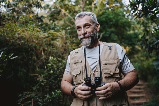 Portrait of a senior man observing nature with binoculars