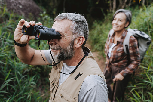 Elderly man observing nature with binoculars