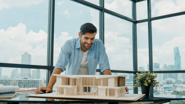 istock Portrait of engineer smiling at camera while inspect house model. Tracery 2148133928