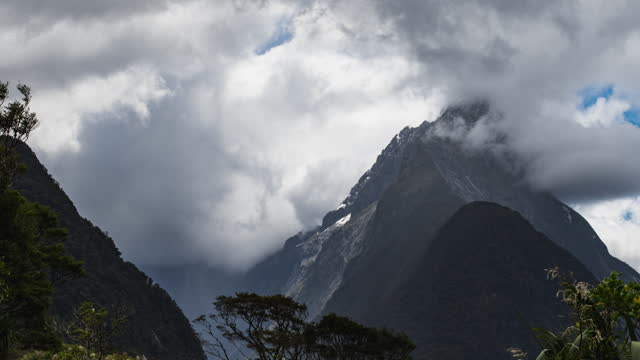 Panning time-lapse of clouds forming around a steep mountain in Milford Sound