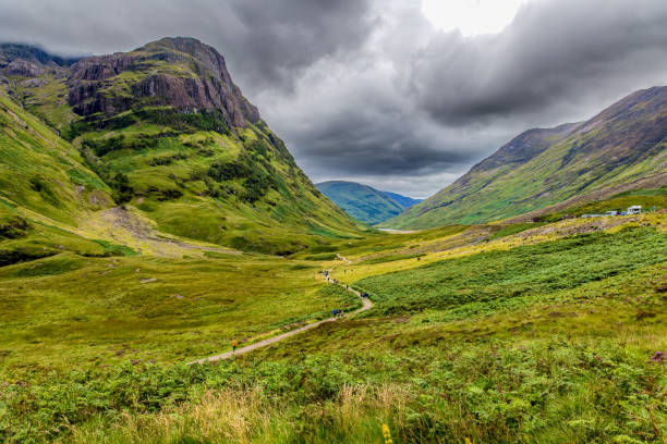 istock Hiking trail leading into a valley surrounded by steep mountains and a stormy, grey sky 2148135367