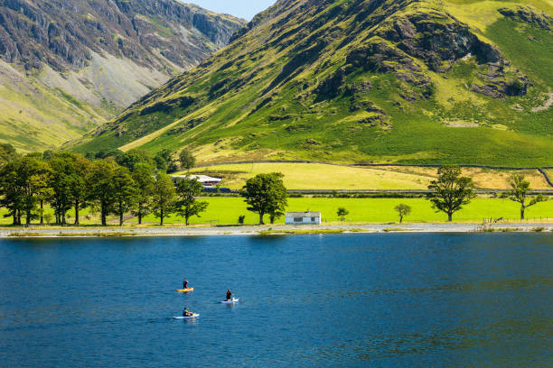 Kayaks and paddleboards on a calm, peaceful lake surrounded by tall mountains (Buttermere, Lake Distrtict)