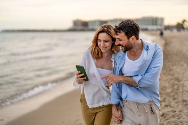 istock Young couple texting at the beach 2148135723
