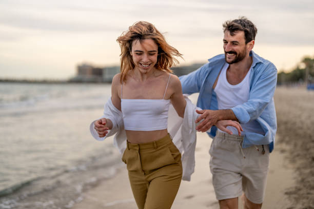istock Beautiful couple running on the beach holding hands 2148135827