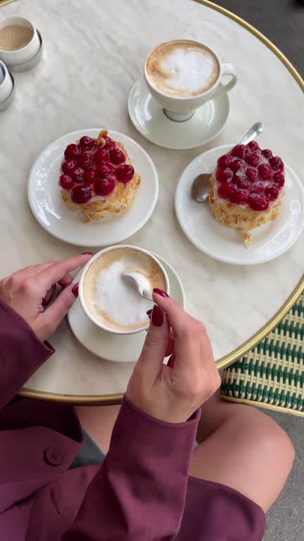 Trendy dressed woman drinking coffee with pastry at the cafe