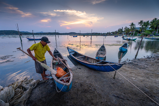 Phu Yen province, Vietnam - 02 April 2024: Traditional fishermen and boats in O Loan lagoon during sunset, Phu Yen province, Vietnam.