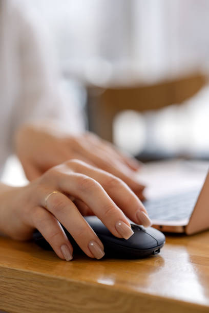 Woman's hand on the mouse near a Macbook Air laptop computer