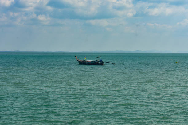 A long tail boat in the middle of sea .