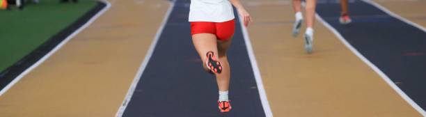 istock Female runners running in lane on an indoor track at a track competition 2148139607