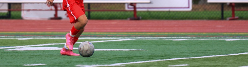 One soccer player dribbling the ball down the field