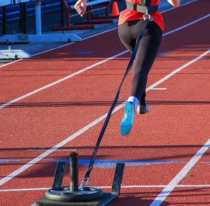 Female runner pulling a weighted sled on a track