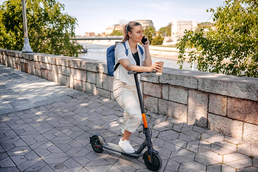 Woman enjoying on sunny day with her electric scooter in public park
