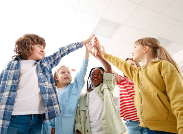 istock Group of smiling school kids making high five in corridor in the school 2148145352