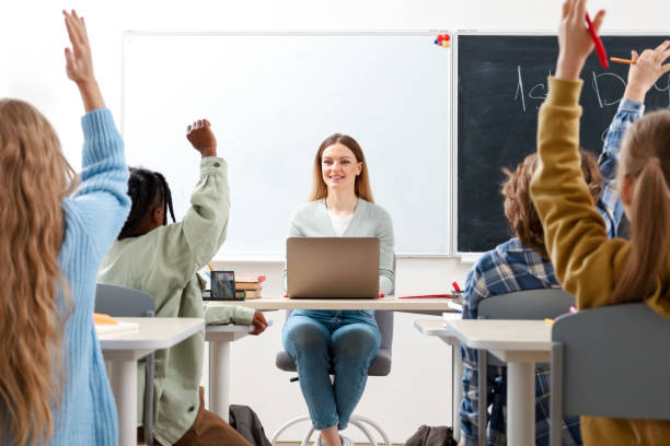 istock Pupils raising their hands during class at elementary school. Education, learning and people concept 2148145357
