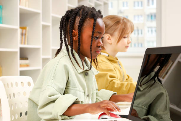 istock School kids sitting at table and working on laptop together during lesson in class 2148145361