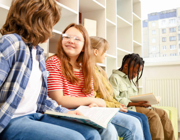 istock Row of happy multiethnic elementary students reading book in classroom 2148145371