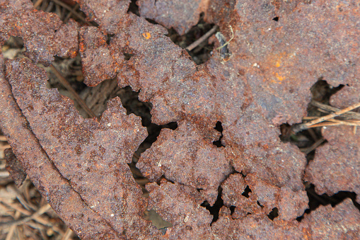 Piece of metal in an advanced state of corrosion, abstract close-up image of a piece of metal with rust.