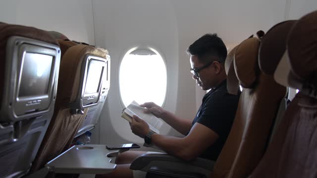man reading a book on airplane