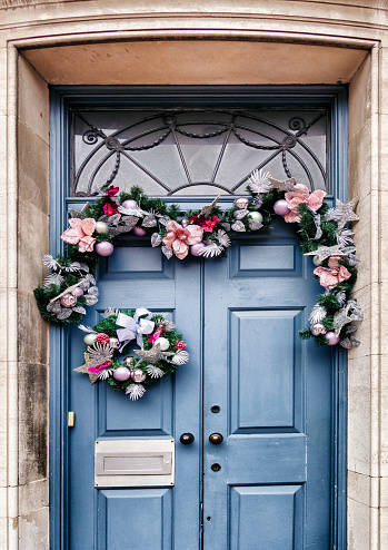 A Christmas garland draped on a painted blue-grey door.