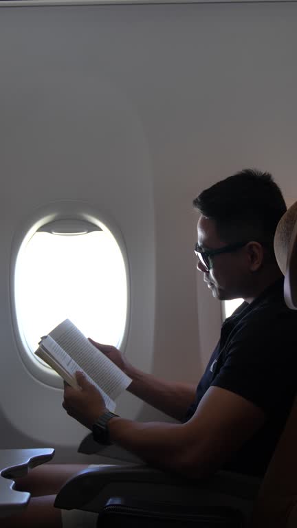 man reading a book on airplane