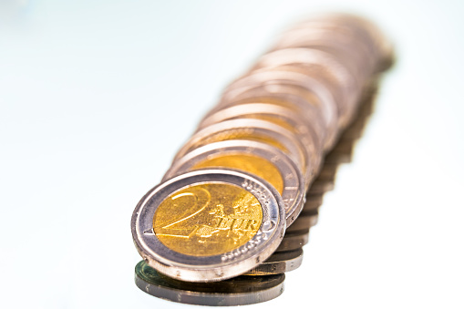 Row of coins on reflective surface, backlight.