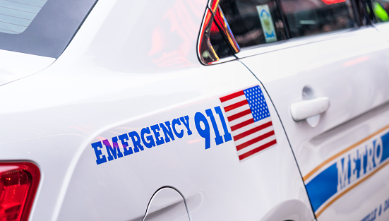 The text Emergency 911 by a stars and stripes flag on the side of a police car in Nashville.