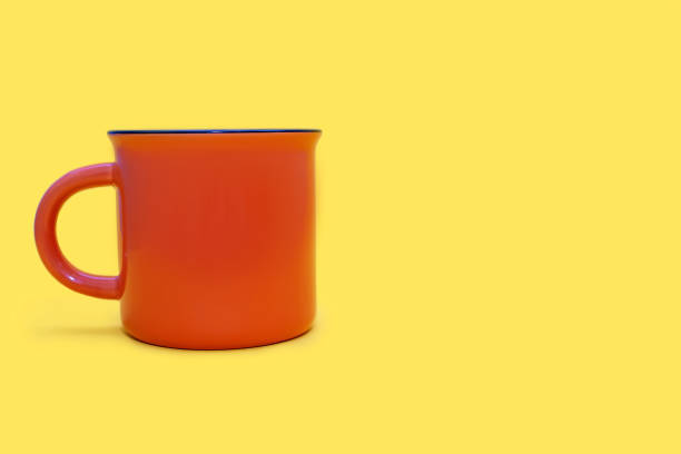 istock Orange mug on a yellow background with free space for text 2148151099