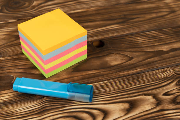 A stack of colorful notes, reminder stickers and a blue marker on a wooden table. organization, planning