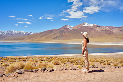 young traveler woman looking enjoying the majestic view of Miscanti lake and mountains in Los Flamencos National Reserve	in San Pedro de Atacama