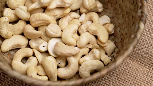 Organic cashew nuts in a rustic wood braid bowl close up. Nutritious dietary ingredients. Rural style view. Rotation