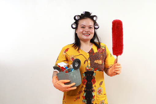 Happy asian housekeeper standing while holding home cleaning tools