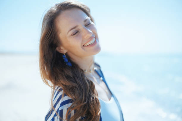 istock smiling stylish woman on ocean shore enjoying tranquility 2148152972