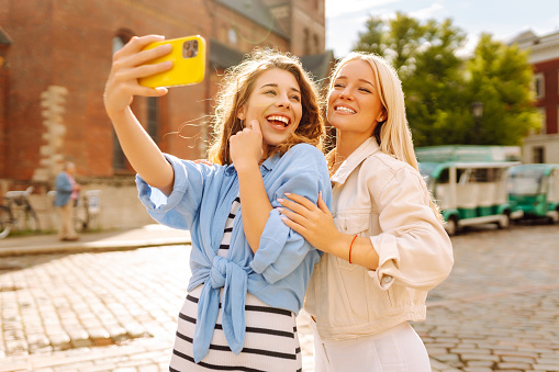 Happy women taking selfie while walking down the street. Fashion, travel, technology, blogging concept.