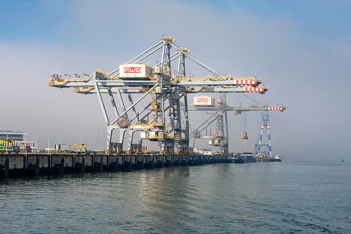 Rotterdam, The Netherlands - March 06, 2024: Large gantry cranes and container ship - port of Rotterdam - Maasvlakte. The Maasvlakte is a massive westward extension of the Europoort port and industrial facility within the Port of Rotterdam.