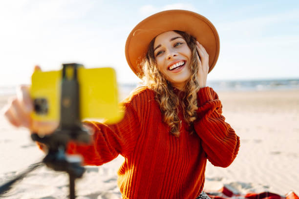 istock Female blogger recording video using smartphone on tripod on the seashore. 2148155423