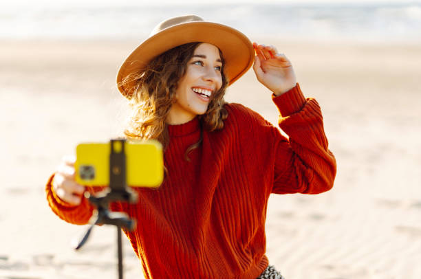 istock Female blogger recording video using smartphone on tripod on the seashore. 2148155432