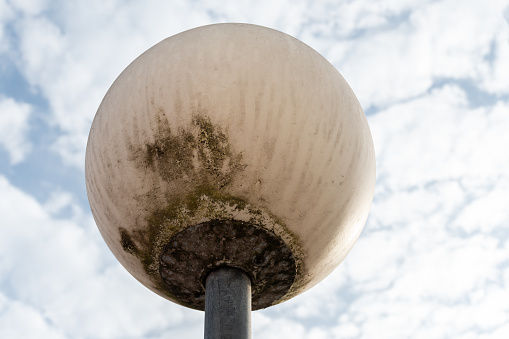 Old, dirty and deteriorated spherical street light.