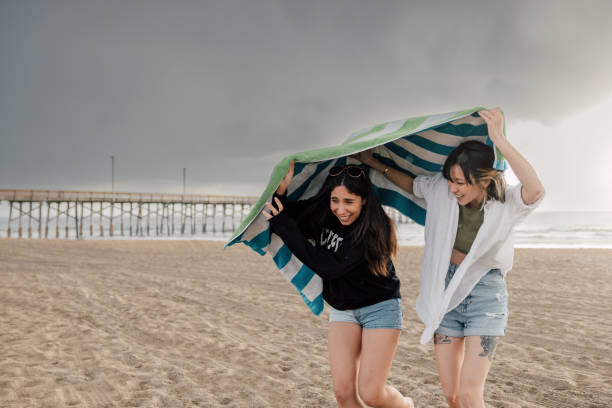 Two friends running away from the beach while is raining