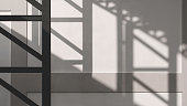 Light and geometric shadow pattern of metal column on surface of concrete building wall background in monochrome and minimal style