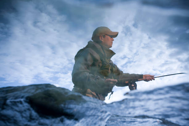 Reflection in a tidal pool of a man fishing off the rocks of Newport, Rhode Island