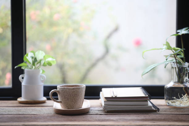 istock Coffee in a white cup and notebooks on wooden table with plants 2148161024